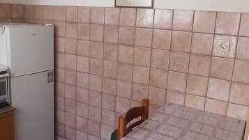 Una cocina pequeña con refrigerador, microondas y salpicadero de azulejos.