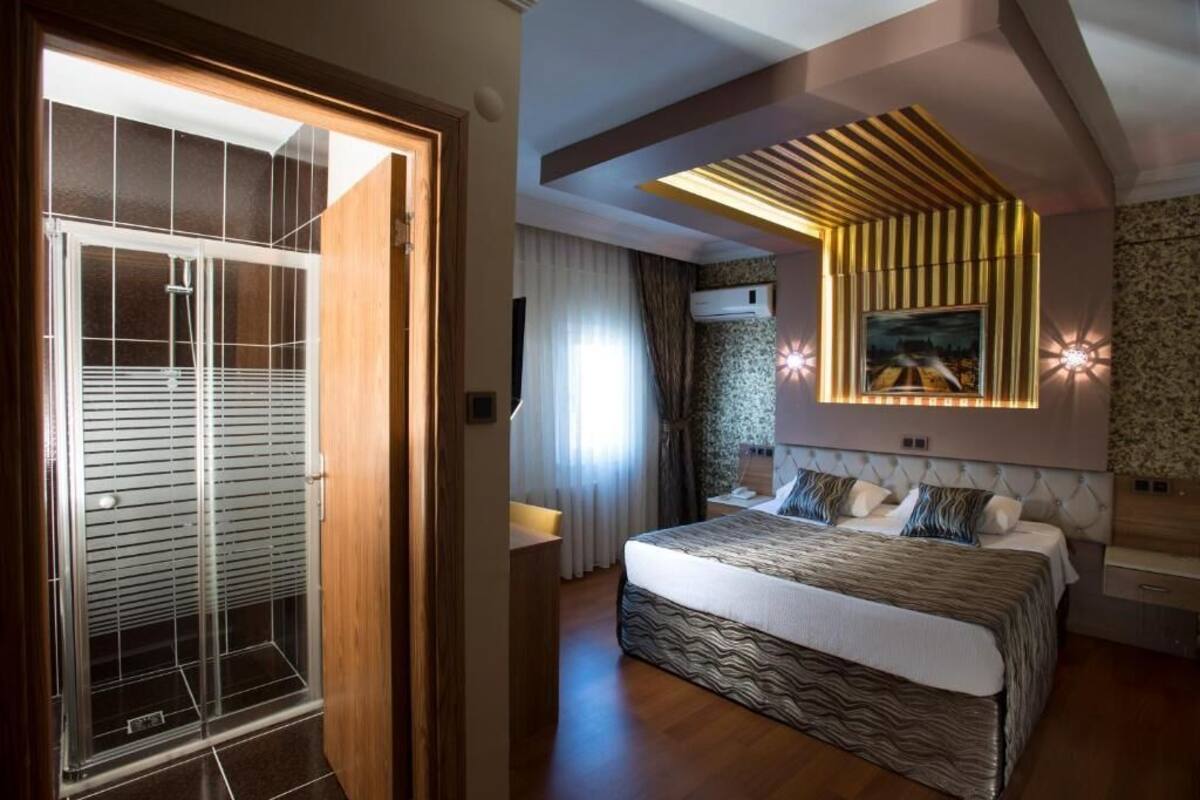 A modern bedroom with a large bed, a built-in wardrobe, and a ceiling with a unique light fixture.
