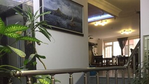 Una scala con ringhiera in metallo, circondata da piante in vaso e sedie rosse.