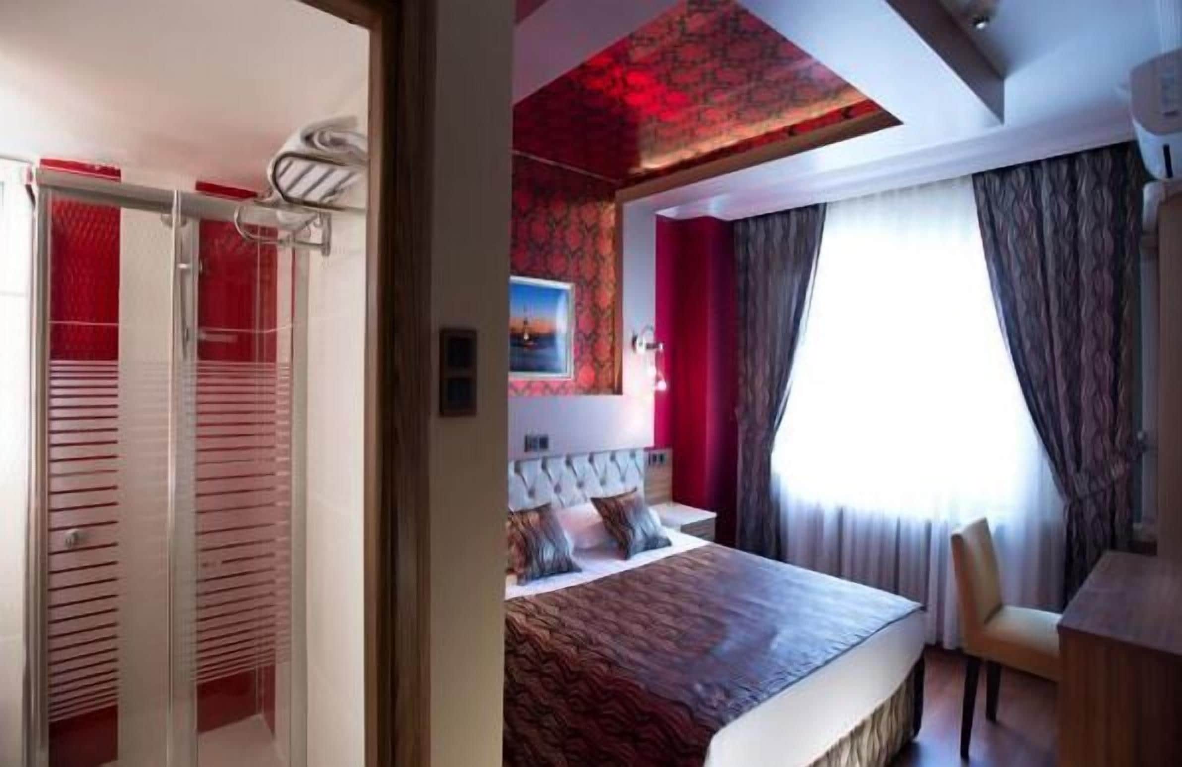 A hotel room with a bed, a desk, and a window with curtains.