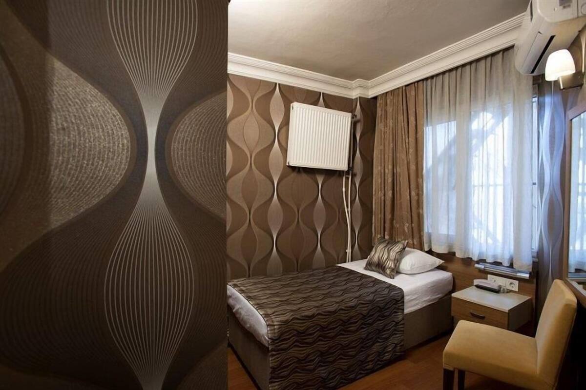 A hotel room with a bed, a desk, a chair, and a radiator.