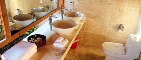 A bathroom with two sinks, a toilet, and a mirror.