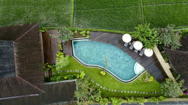 An aerial view of a backyard with a swimming pool, surrounded by a wooden deck, and a small garden area with plants and a stone pathway. - Kabinawa Ubud Villas by GenuineHost (Tegallalang)