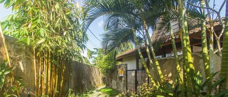 A narrow pathway with stepping stones leading to a building with a tiled roof and a visible balcony.