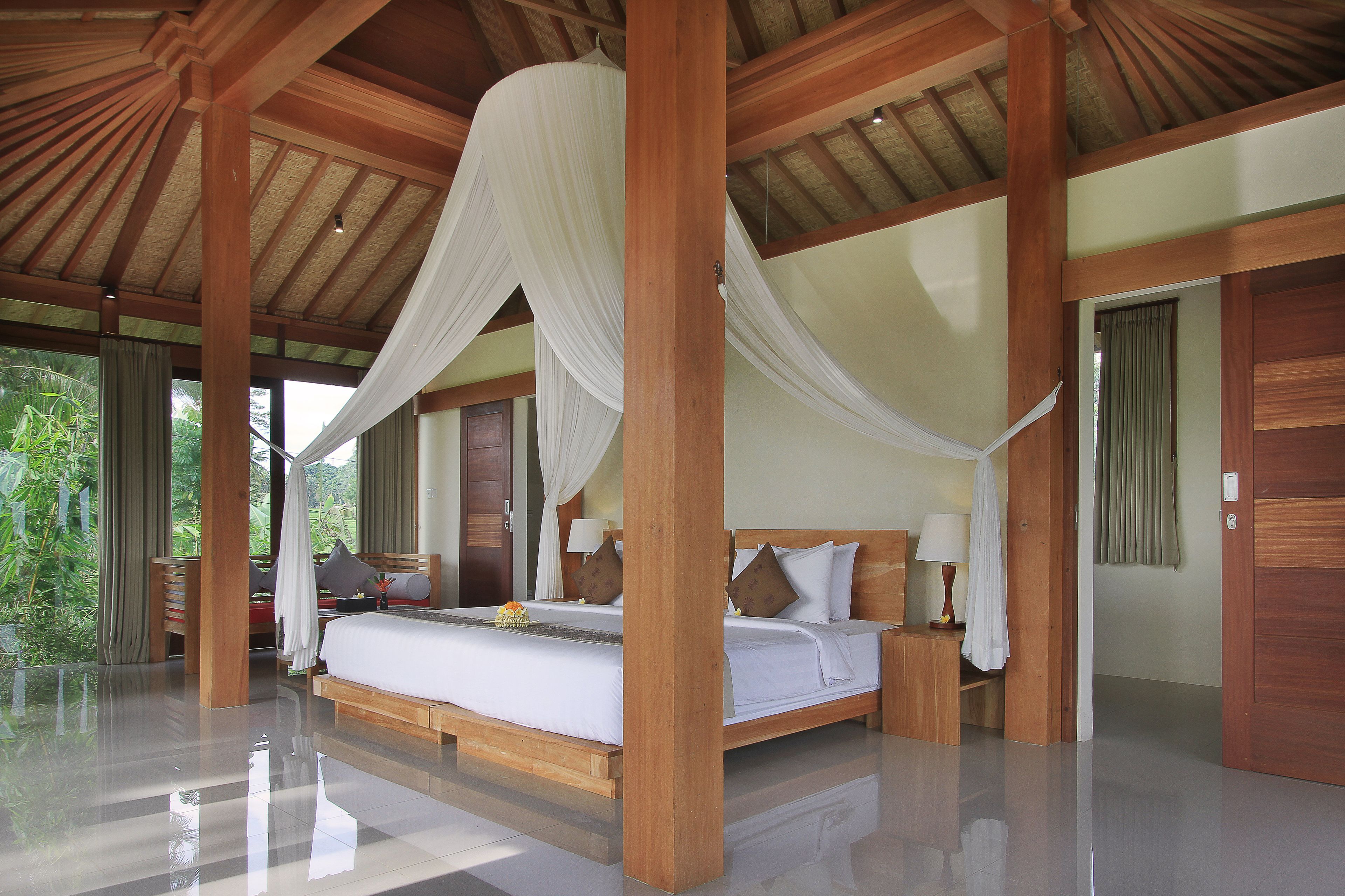 Ein geräumiges Schlafzimmer mit einem großen Bett, Holzbalken und Blick auf Grünflächen.