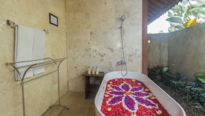 Un baño con ducha independiente, un perchero y una mesita con artículos de aseo.
