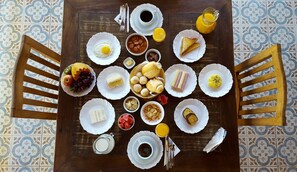 A table set with various breakfast items including eggs, fruits, bread, and beverages.