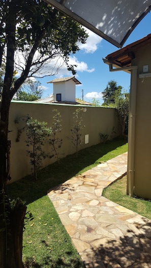 A stone pathway leading to a building with a tiled roof, surrounded by a well-maintained lawn and trees. - Pousada Makutta (Ouro Preto)