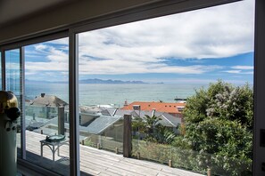 A large window with a view of the sea and mountains. - Kalk Bay Apartments (Cape Town)