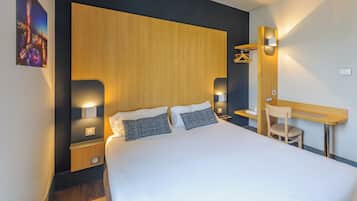 Ein Hotelzimmer mit einem großen Bett, Nachttischen, einem Schreibtisch und einem Sessel.