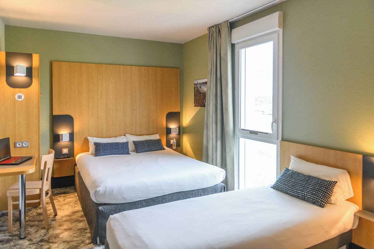 Ein Hotelzimmer mit zwei Betten, einem Schreibtisch und einem Stuhl.