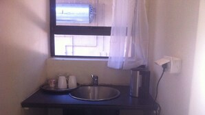 Een kleine badkamer met een wastafel, een raam met gordijnen en een stopcontact.