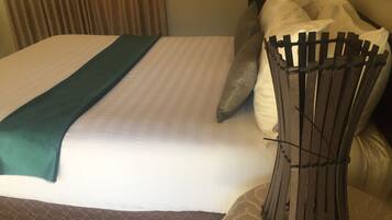 Ein Hotelzimmer mit Bett, Kissen, Kopfteil und einem dekorativen Sessel.