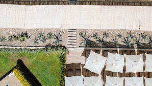 An aerial view of a beachside resort with umbrellas, lounge chairs, and a pathway leading to the beach. - YAZ Yalikavak (Bodrum)