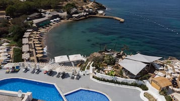 Una piscina al aire libre, sombrillas, sillones reclinables de piscina