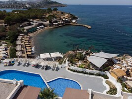 Una piscina al aire libre, sombrillas, sillones reclinables de piscina