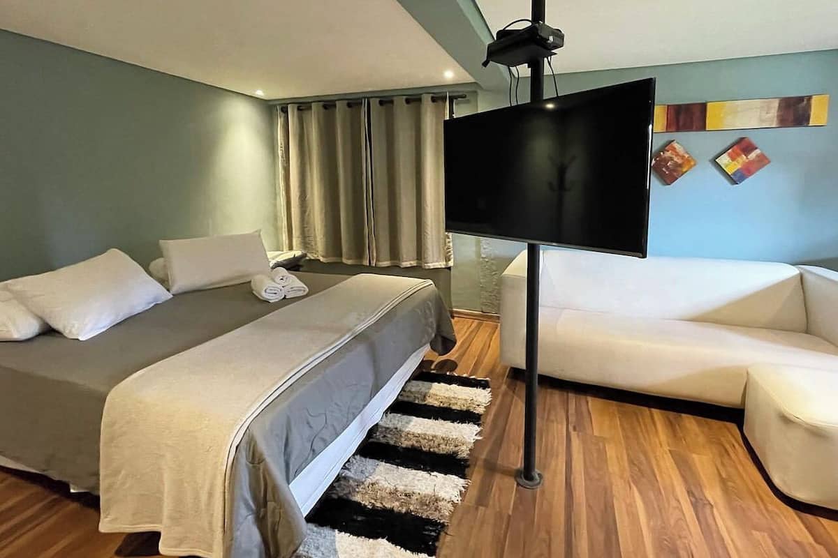 Une chambre d’hôtel moderne équipée d’un lit, d’un canapé, d’une télévision et d’un plancher en bois.
