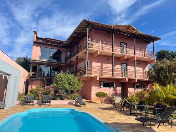 Una piscina al aire libre, sombrillas, sillones reclinables de piscina