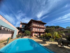 Una piscina al aire libre, sombrillas, sillones reclinables de piscina