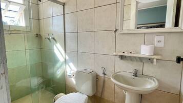 Een badkamer met toilet, wastafel en een douchecabine met glazen wanden.