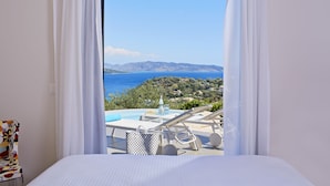 Una camera da letto con un letto, una sedia e vista sul mare e sulle colline.