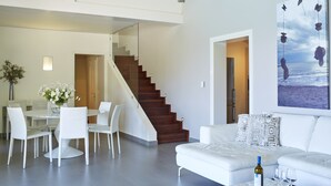 Un soggiorno moderno con un divano bianco, un tavolo da pranzo con sedie e una scala che conduce a un altro piano.