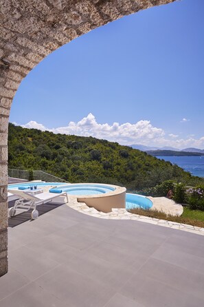 Zona de piscina con vista al mar y colinas.