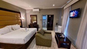 Ett hotellrum med en säng, en soffa, ett litet bord, en tv och en spegel.
