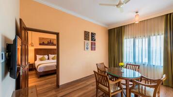 Une chambre d’hôtel comprenant un lit, une table à manger avec des chaises, un ventilateur de plafond et un téléviseur.