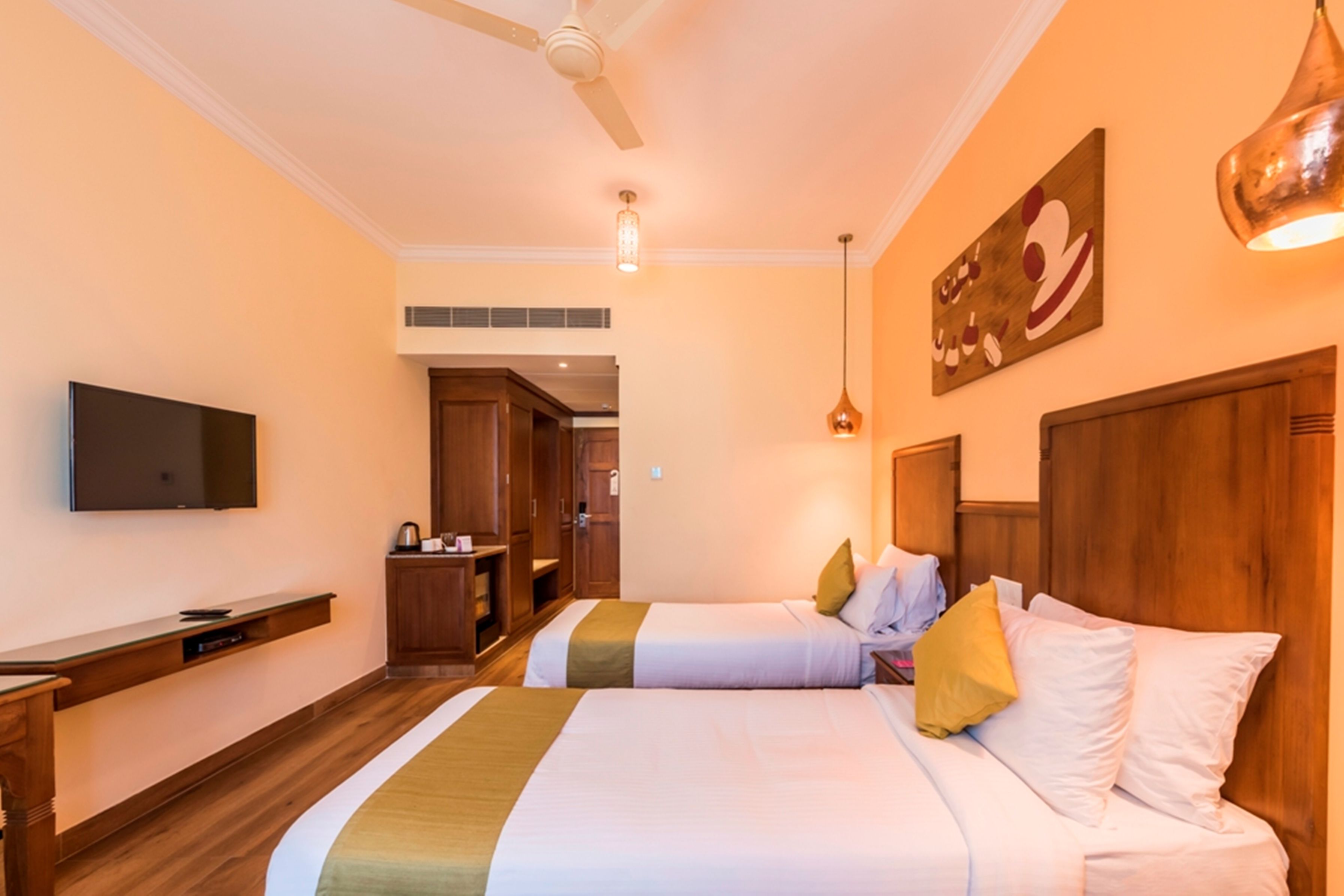 Una habitación de hotel con dos camas, televisión, muebles de madera y un cuadro en la pared.