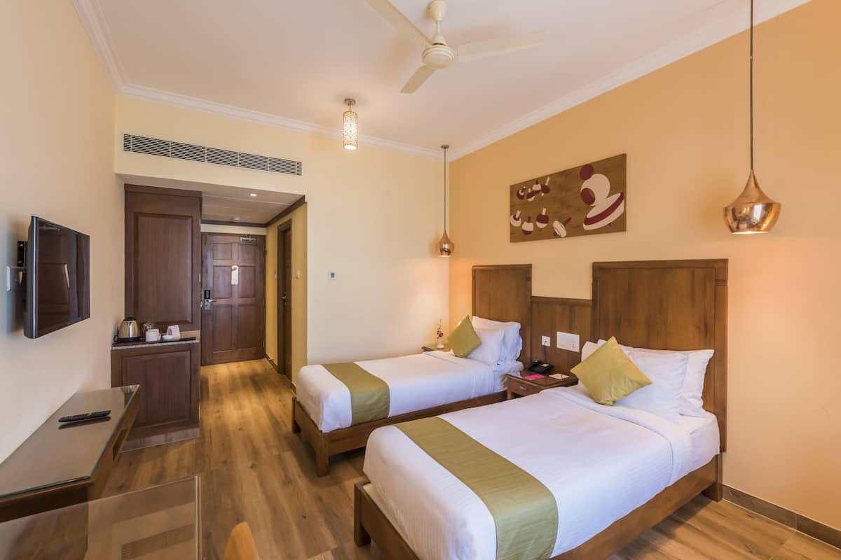 Una habitación de hotel con dos camas, un escritorio, un televisor y un ventilador de techo.