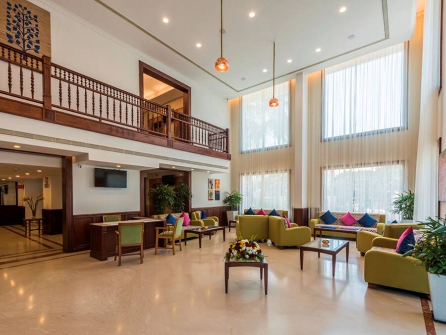 A spacious lobby with a high ceiling, a balcony, and large windows allowing natural light.