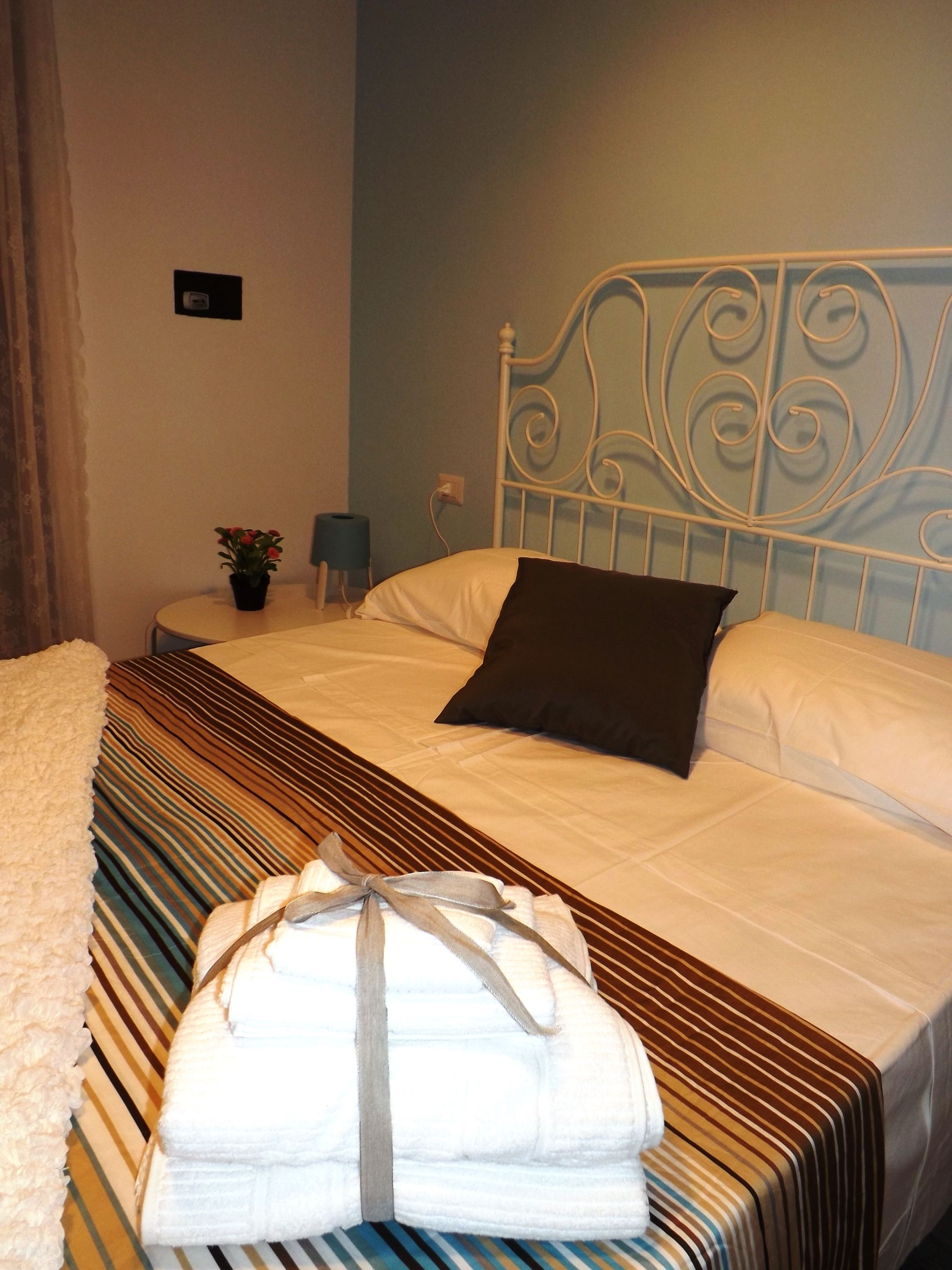 A neatly made bed with a striped bedspread, a pillow, and a folded towel on the side.