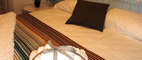 A neatly made bed with a striped bedspread, a pillow, and a folded towel on the side.