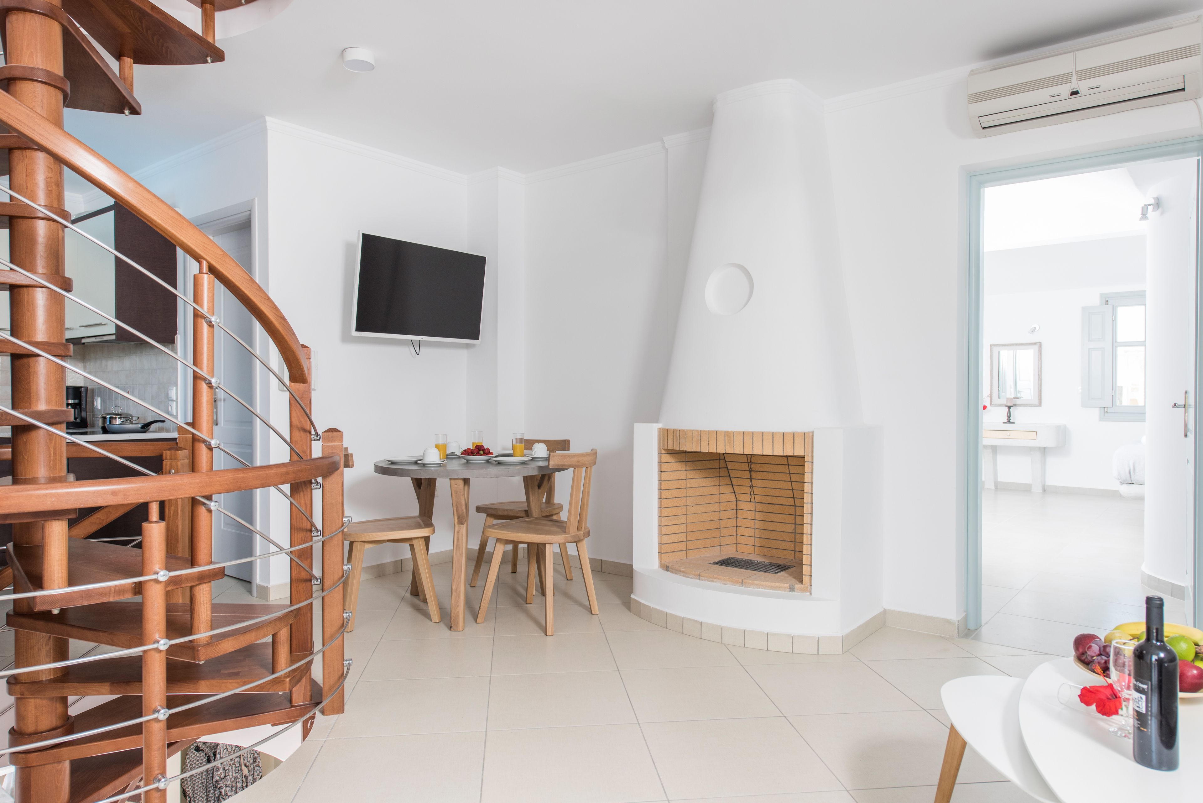 Ein modernes Interieur mit Wendeltreppe, Kamin, Essbereich und an der Wand montiertem Fernseher.