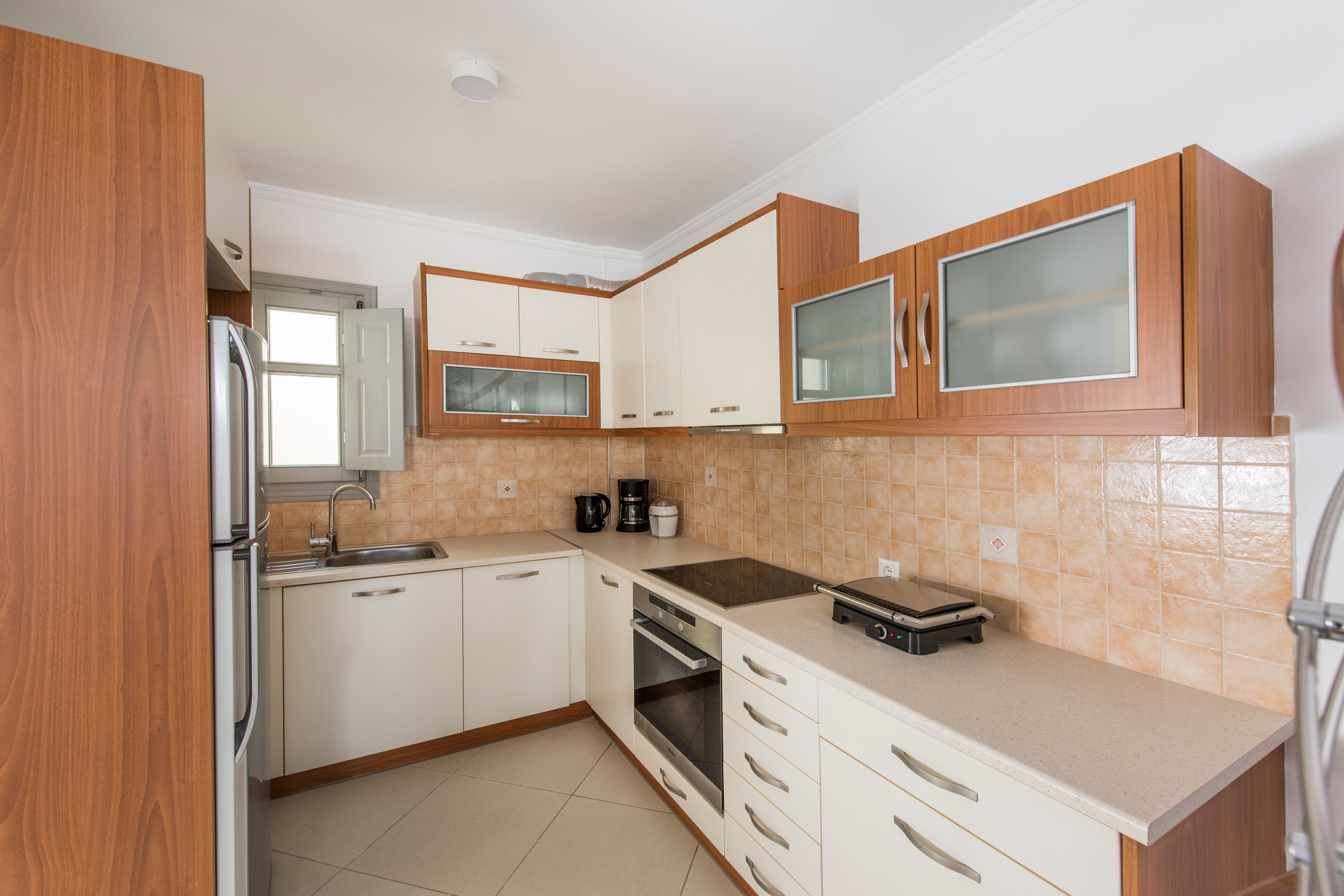 A modern kitchen with white cabinets, a stainless steel refrigerator, a built-in oven, and a microwave.