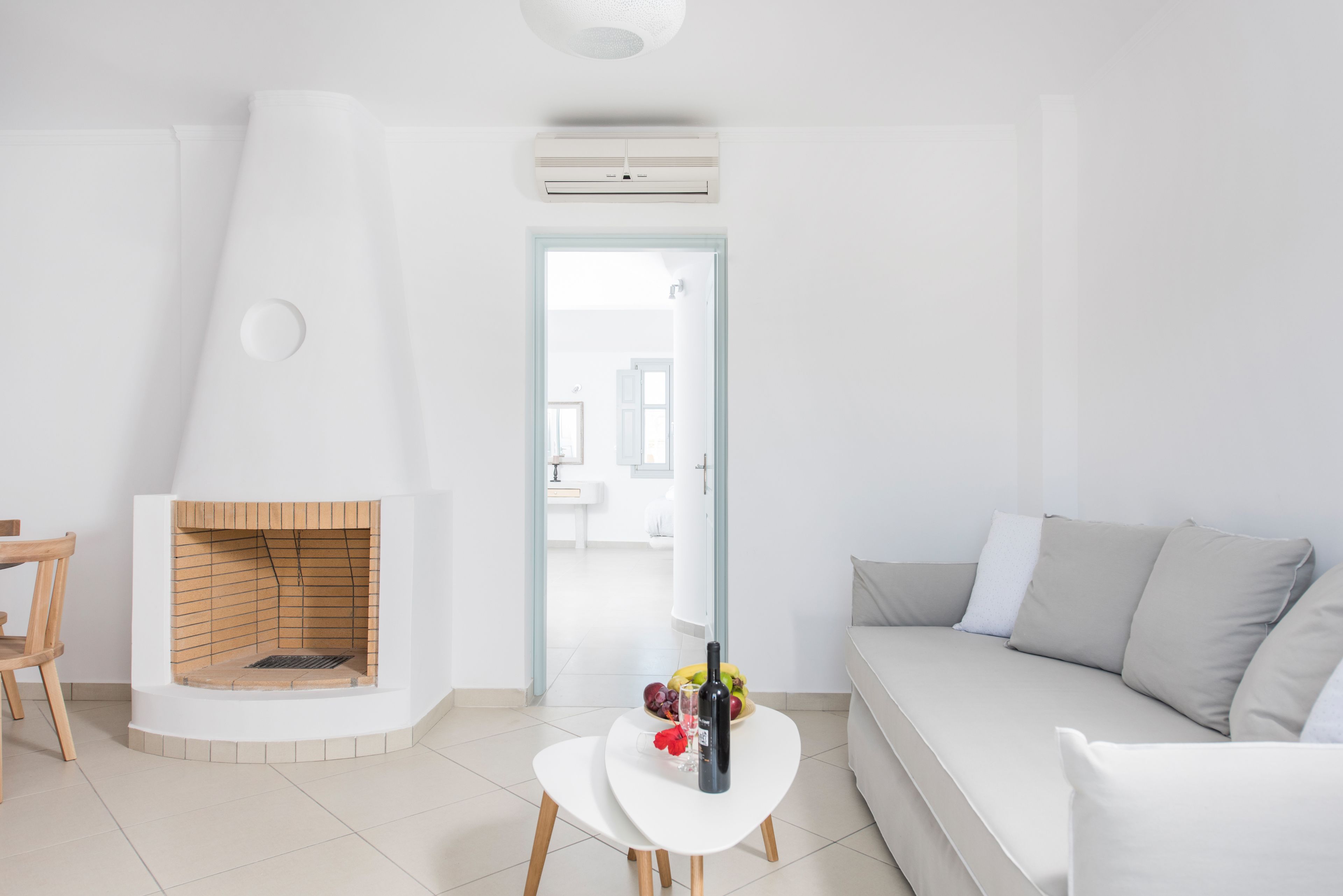 A modern living room with a built-in fireplace, a white sofa, a small white table, and a wooden chair.