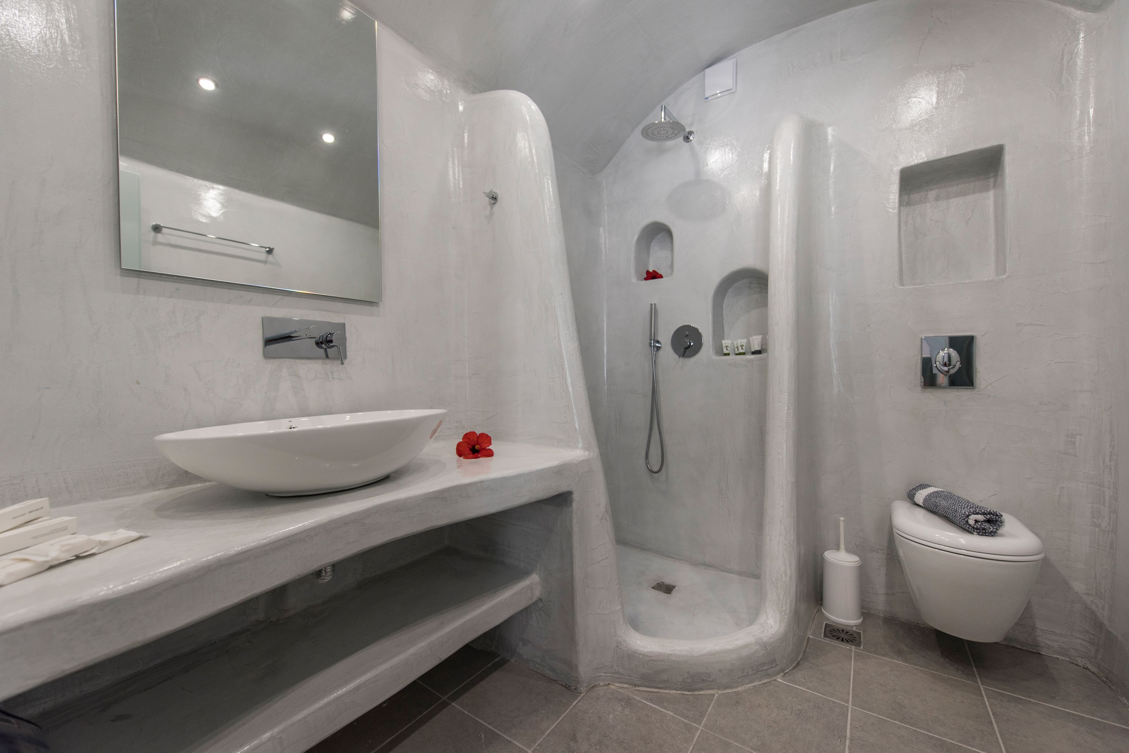 Un baño moderno con un lavamanos grande blanco, un espejo, cabina de ducha y un inodoro.