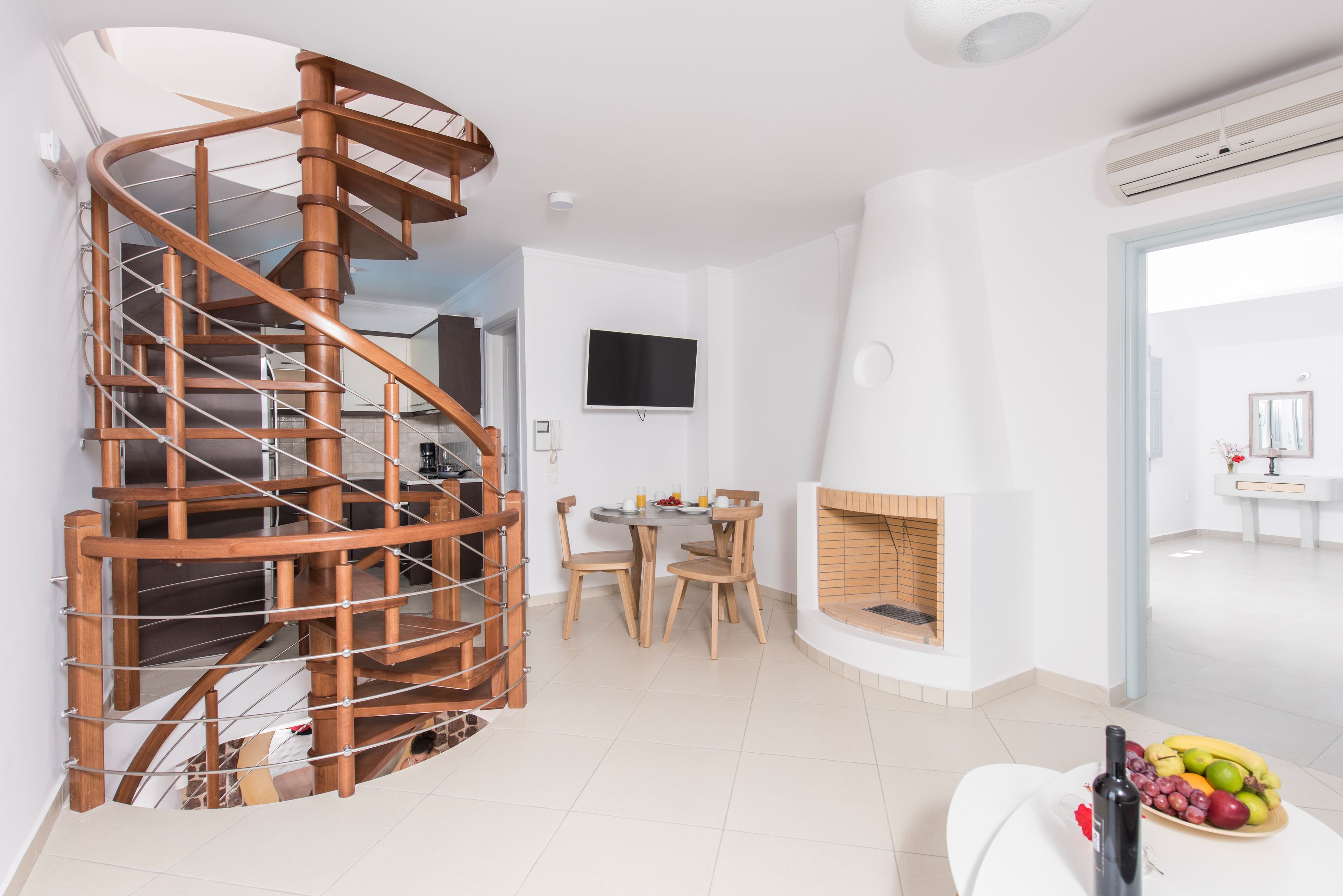 A modern interior with a spiral staircase, a fireplace, a dining area, and a TV mounted on the wall.