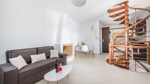 A modern living room with a brown sofa, a white coffee table, and a spiral staircase. - Secret Earth Santorini (Santorini)