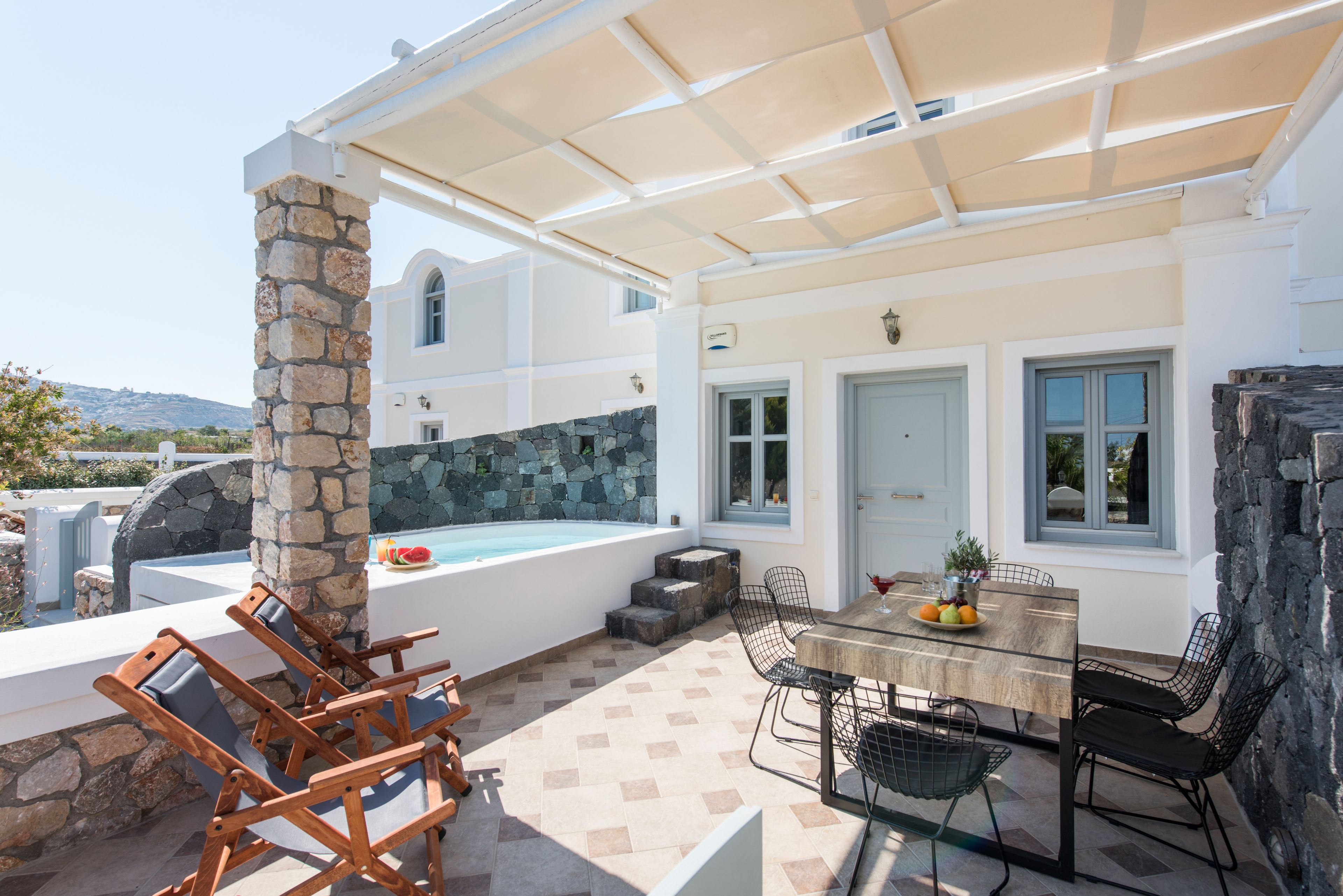 A covered outdoor area with a pool, stone pillar, and seating.
