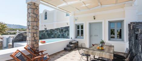 A covered outdoor area with a pool, stone pillar, and seating.