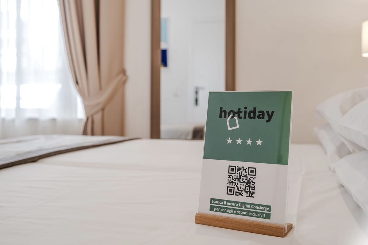 Segnaletica su un letto in camera d'albergo che pubblicizza un servizio di concierge digitale.