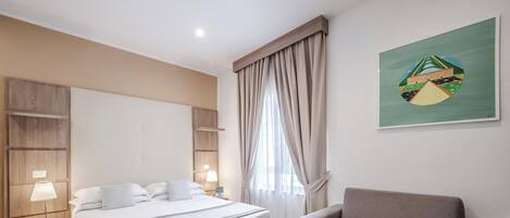 Habitación de hotel con cama, una silla, un cuadro y una ventana con cortinas.