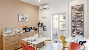 A dining area with a wooden buffet, a coffee machine, and a large framed photo of a market scene. - Residenza Scarlatti (Naples)