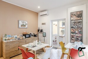 A dining area with a wooden buffet, a coffee machine, and a large framed photo of a market scene. - Residenza Scarlatti (Naples)