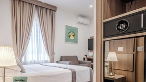 A hotel room with a bed, a chair, a desk, a lamp, and a minibar. - Residenza Scarlatti (Naples)