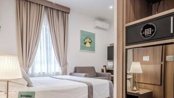 Habitación de hotel con cama, escritorio, silla, aire acondicionado, espejo y un cartel con un código QR.