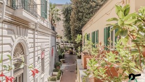 A narrow street with buildings on either side, featuring balconies with green shutters and potted plants. - Residenza Scarlatti (Naples)