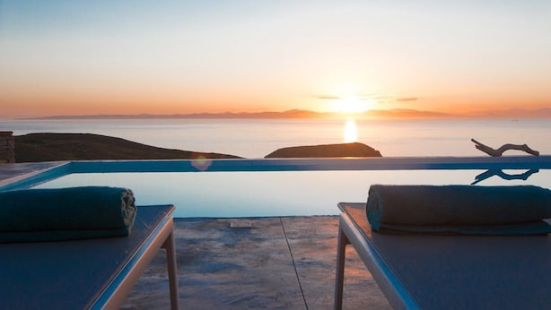 Une vue sur le coucher de soleil depuis un balcon, avec deux chaises longues et une serviette.